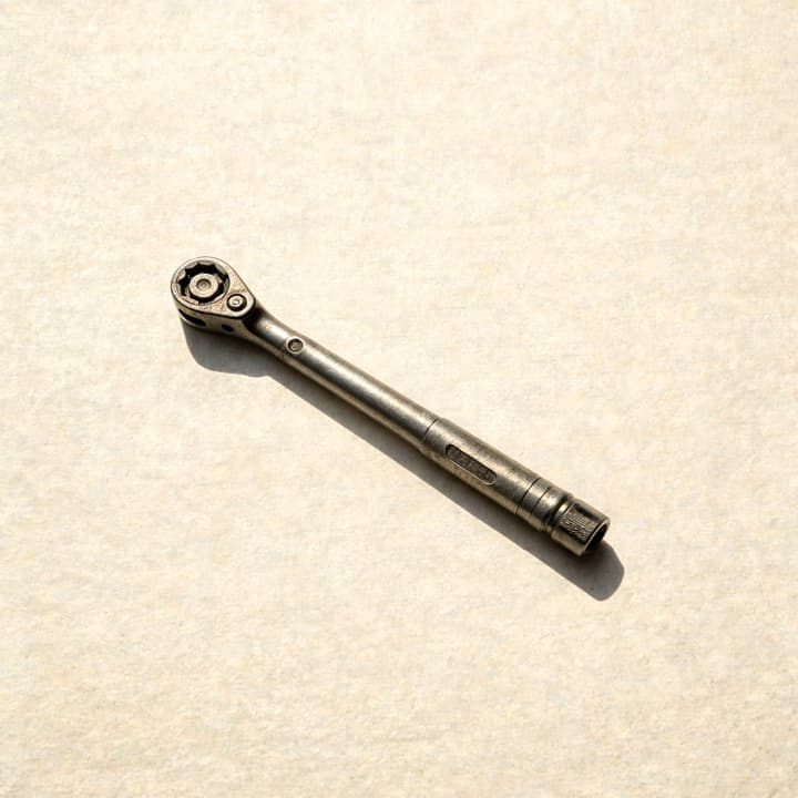 A well-used torque wrench, photographed on bone-coloured paper.